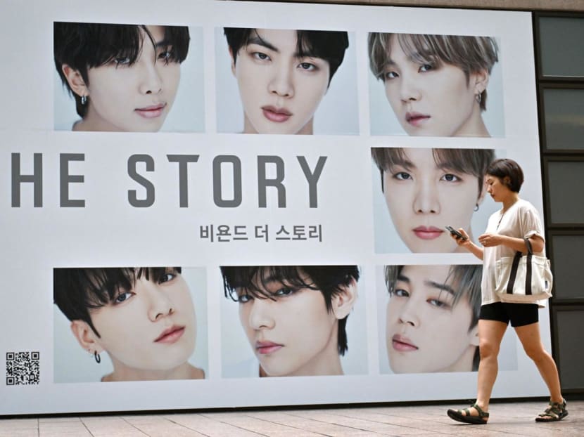 A woman walks past a poster for the BTS memoir titled "Beyond the Story: 10-Year Record of BTS" in front of a bookstore in Seoul on July 9, 2023.