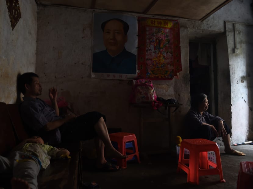 This photo taken on May 8, 2016 shows a family in their house with a portrait of late communist leader Mao Zedong in the old town of Wuxuan, in south China's Guangxi province. Photo: AFP