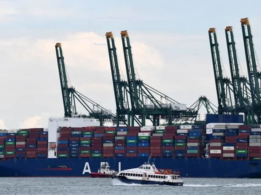 A ferry boat sails past a container vessel docking at a port in Singapore on Aug 17, 2020.