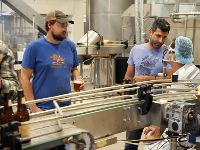 In this Tuesday, Sept. 6, 2016 photo, Yazan Karadsheh, right, founder of the Carakale Brewery in Fuheis, Jordan, talks to a technician while head brewer Jordan Wambeke quality tastes beer off the assembly line. The Jordanian microbrew is starting to export to the United States its signature blonde, Indian pale ale, and a coffee porter dosed with roasted cardamom. Photo: AP
