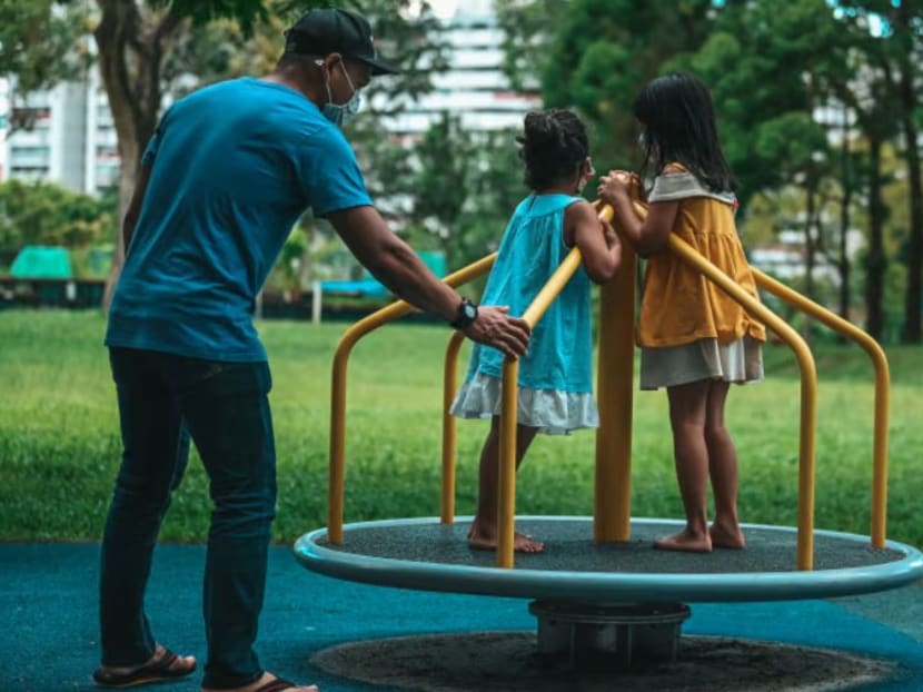 A father playing with his children at a playground in Singapore. 
