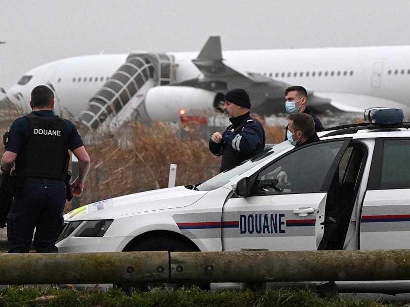 French customs officers at the Vatry airport in north-eastern France on December 25, 2023, with an Airbus A340 in the background which was grounded on the tarmac since December 21 over suspected "human trafficking".