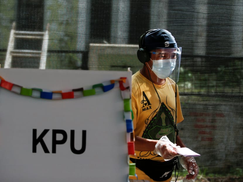 A voter wearing a protective masks and a face shield walks after mark his ballots at a polling booth during regional elections in Tangerang, near Jakarta, Indonesia, Dec 9, 2020.