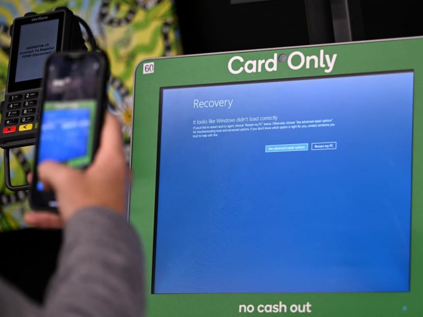 A man takes a picture of a blue error screen at a supermarket self-checkout terminal in Sydney on July 19, 2024.