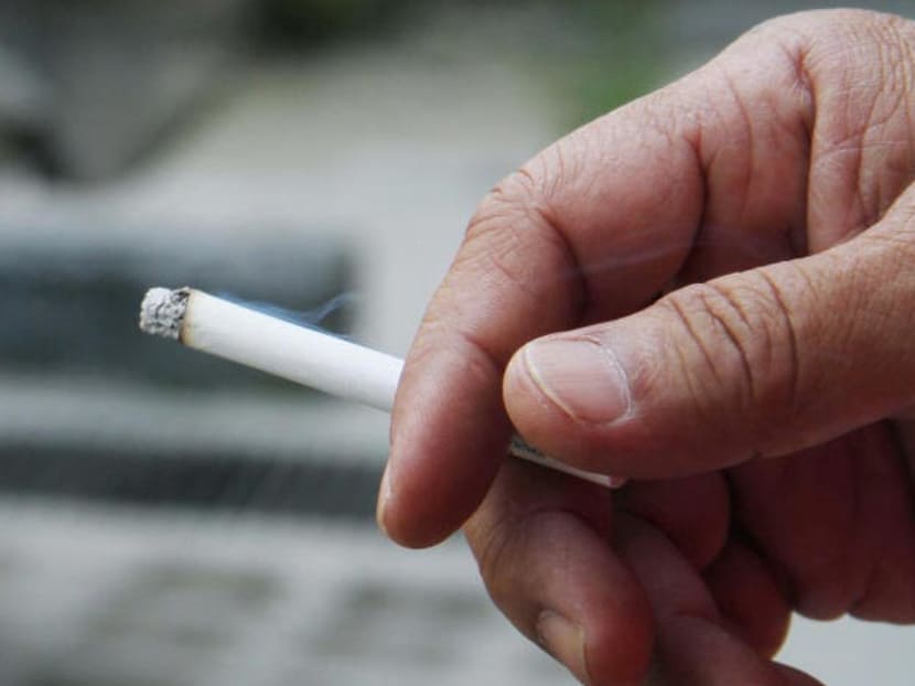 A smoker holding a fresh cigarette casually between his fingers.