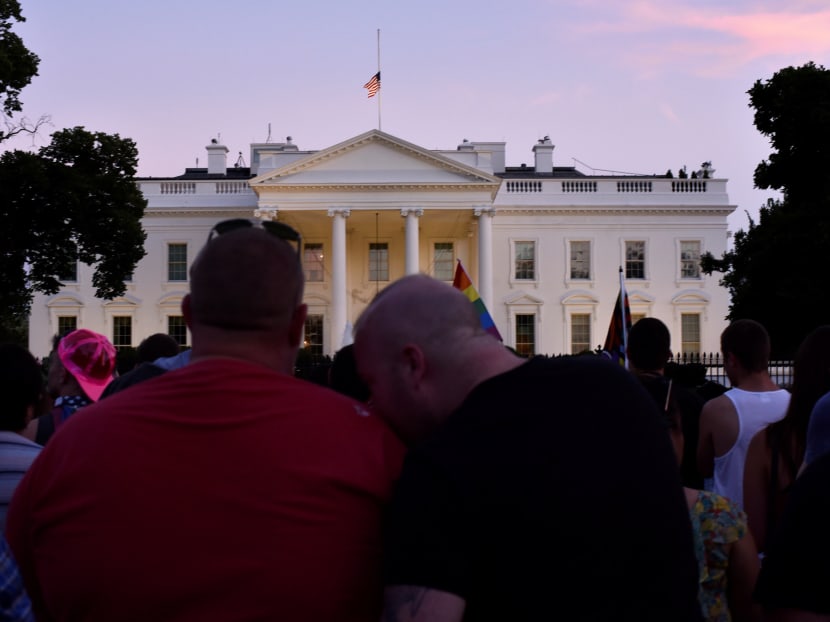 A couple embraces outside the White House where the U.S. flag flies at half-staff at sundown as people gather for a vigil on Pennsylvania Avenue later in the day of the deadliest mass shooting in U.S. history at a gay nightclub in Orlando, Florida in Washington June 12, 2016. Photo: Reuters