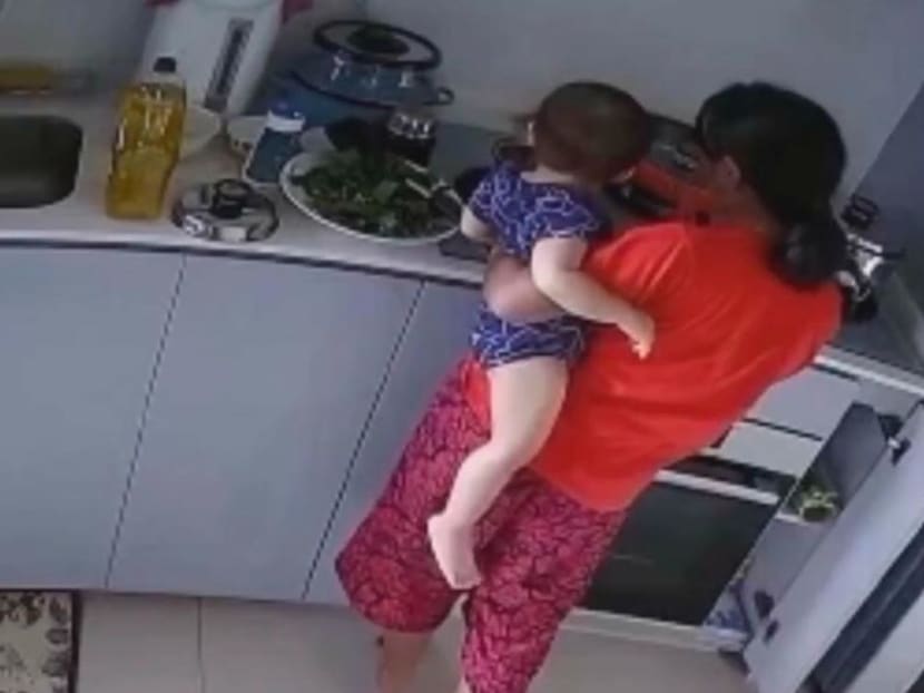 A still photograph taken from CCTV footage of the 30-year-old maid dipping a toddler's hand into a hot pot on a stove.