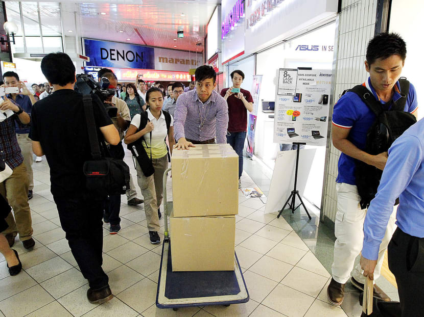 Plain-clothes officers leaving a raided shop yesterday. The two shops that were raided were De.Mac Gadget, registered as Mobile Apps, at #01-50 and Gadget Terminal at #02-80. 
Photo: Ernest Chua