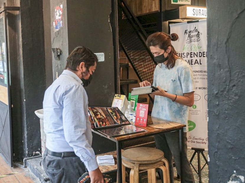 A customer browses through Konda Kondi Cafe and Bistro's menu in Ipoh