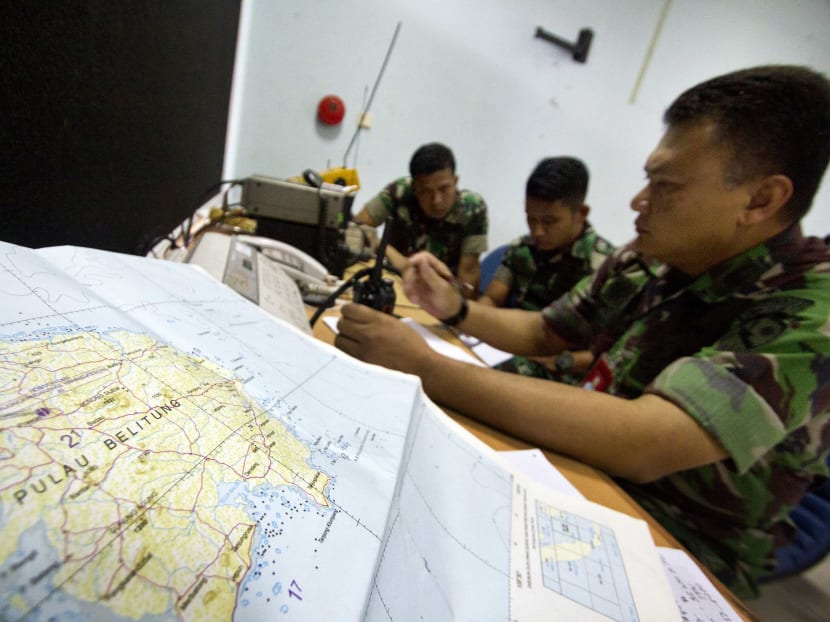 Army soldiers sit near a map of Belitung island while monitoring search operations for AirAsia flight QZ8501 at Halim Perdanakusuma airport in Jakarta. Photo: Reuters
