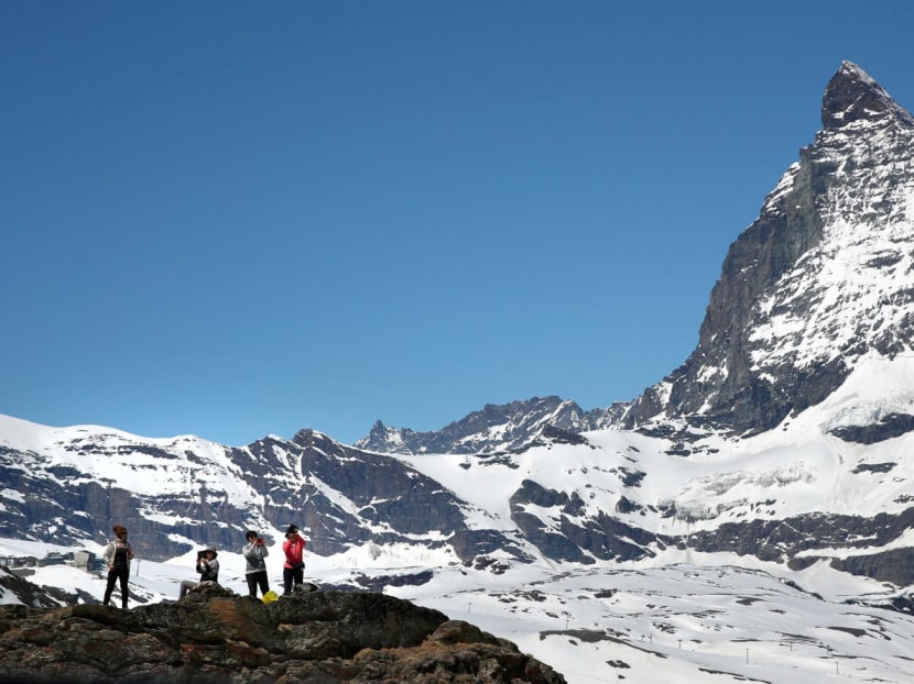 Tourists take a picture in front of the Matterhorn mountain at the Gornergrat in Zermatt, Switzerland on June 2, 2019.