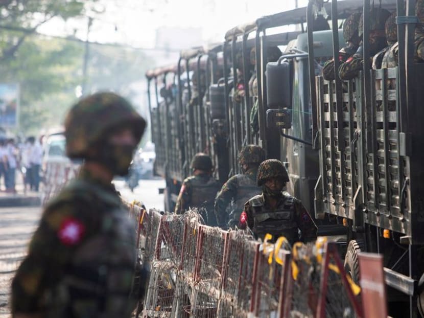 Soldiers stand next to military vehicles as people gather to protest against the military coup, in Yangon, Myanmar, on Feb 15, 2021.