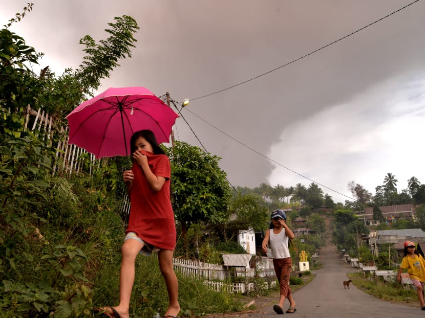 Villagers walk as Mount Soputan volcano spews volcanic ash at Kota Menara village in South Minahasa, North Sulawesi, Indonesia, October 3, 2018.