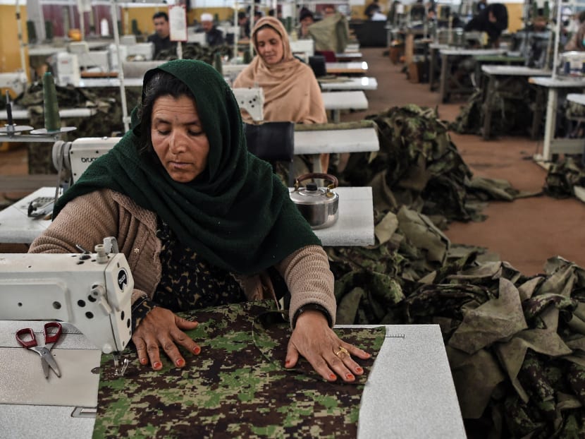 Women who lost their husband or relatives in the ongoing war in Afghanistan with the Taliban stitch military uniforms at a factory in Kabul on Feb 8, 2021.