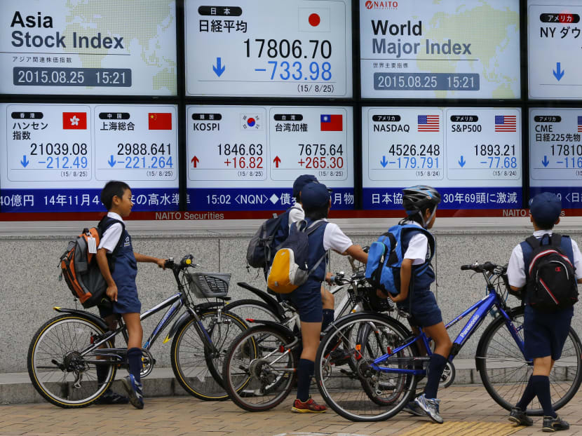 Schoolchildren look at an electronic stock indicator of a securities firm in Tokyo, Aug 25, 2015. Photo: AP