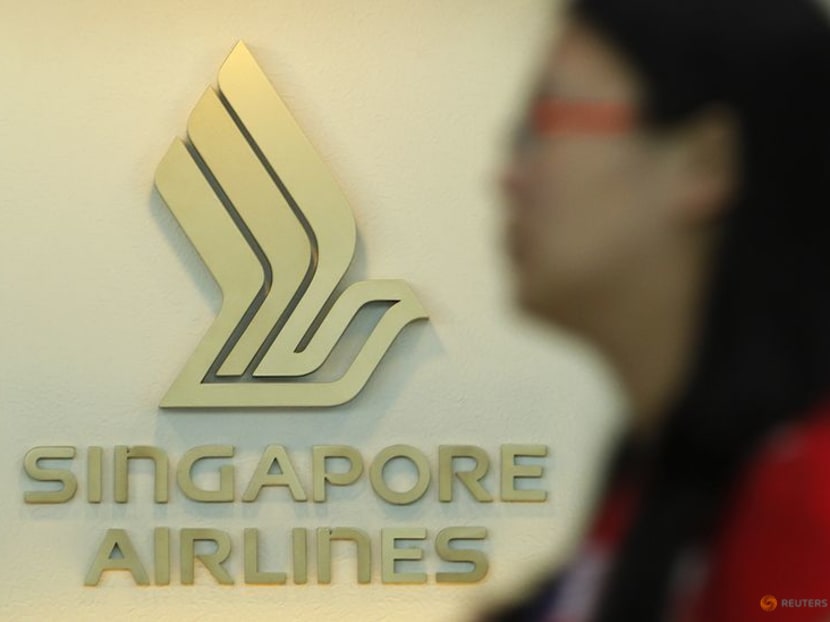 A woman walks past a Singapore Airlines (SIA) logo at a ticketing booth at Changi airport in Singapore.