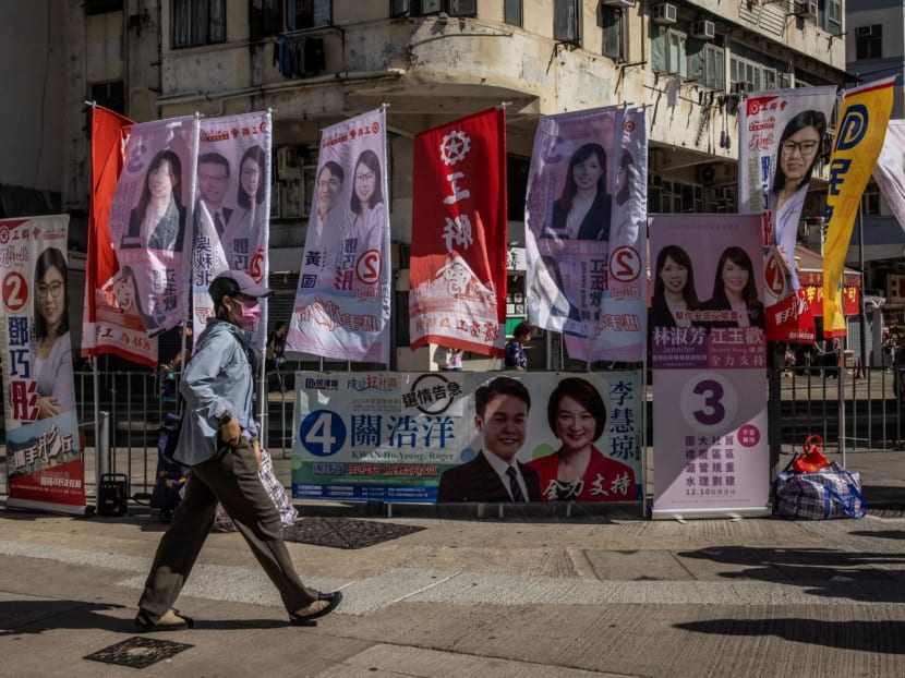 A man walks past signs for candidates during the district council election in Hong Kong on Dec 10, 2023.