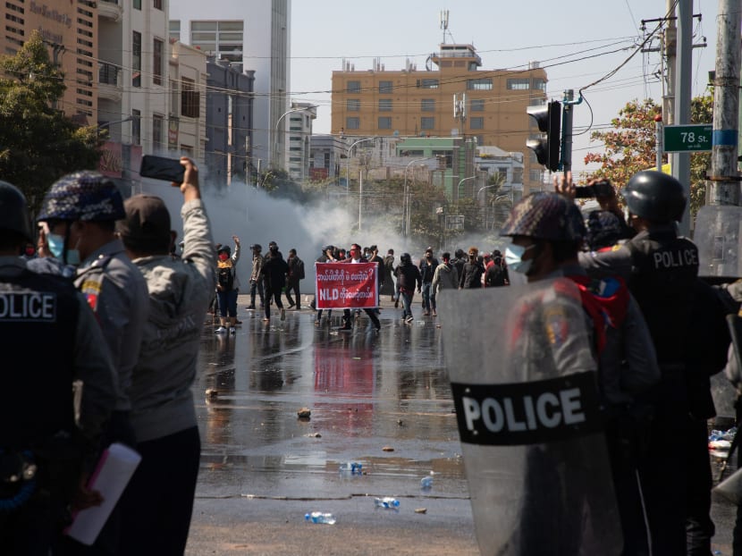 A protester holds up a National League for Democracy banner in front of a police line during a demonstration against the military coup in Mandalay on Feb 9, 2021.